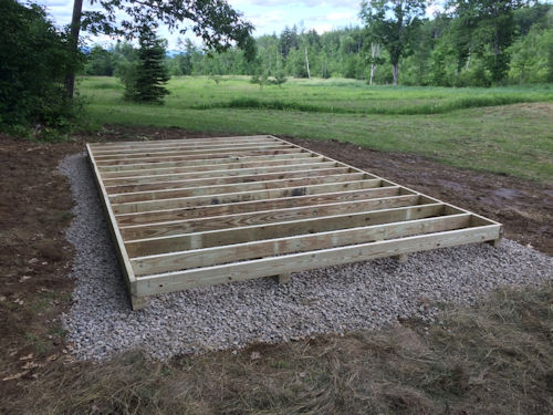 Floor framing resting on crushed rock foundation. Treated floor framing.
